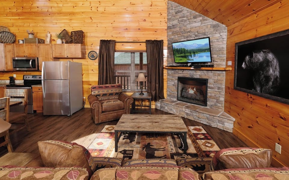 Open living area with kitchen, stone fireplace, and cozy cabin decor.