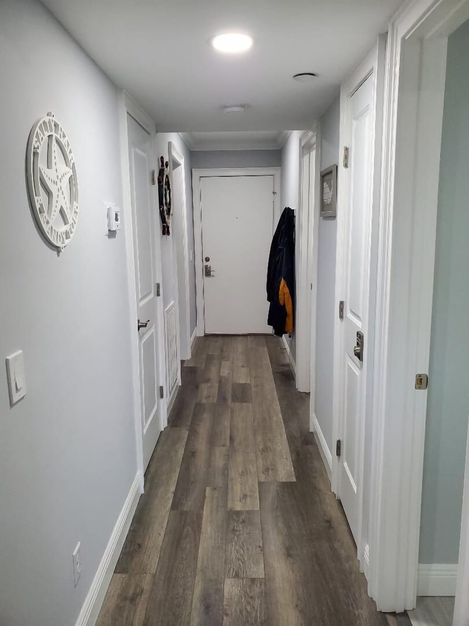Hallway with wall coat rack. Luxury vinyl flooring throughout except tiled baths