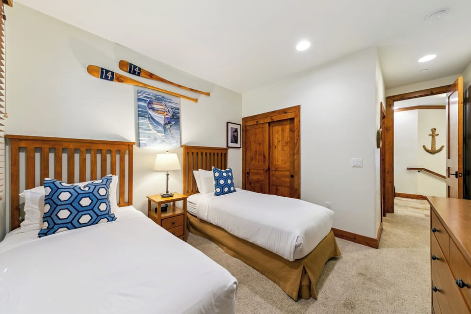 Drift off to sleep in this charming nautical-themed bedroom with twin beds, crisp linens, and ski decor that captures mountain adventure spirit.