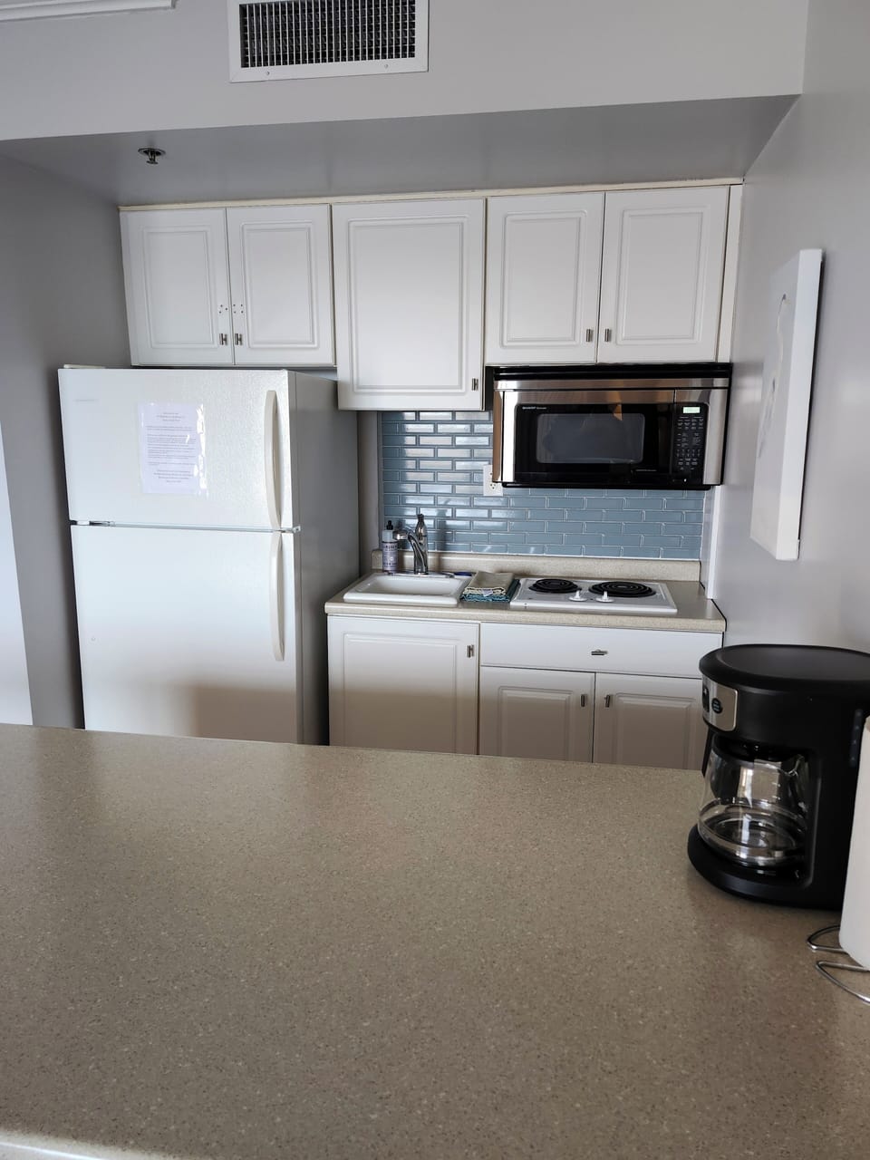Spacious bar with three stools and view of kitchen.