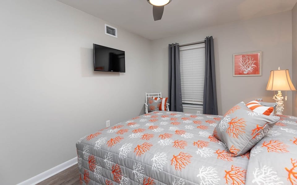 Relax in this inviting guest bedroom featuring a queen bed and a wall-mounted TV