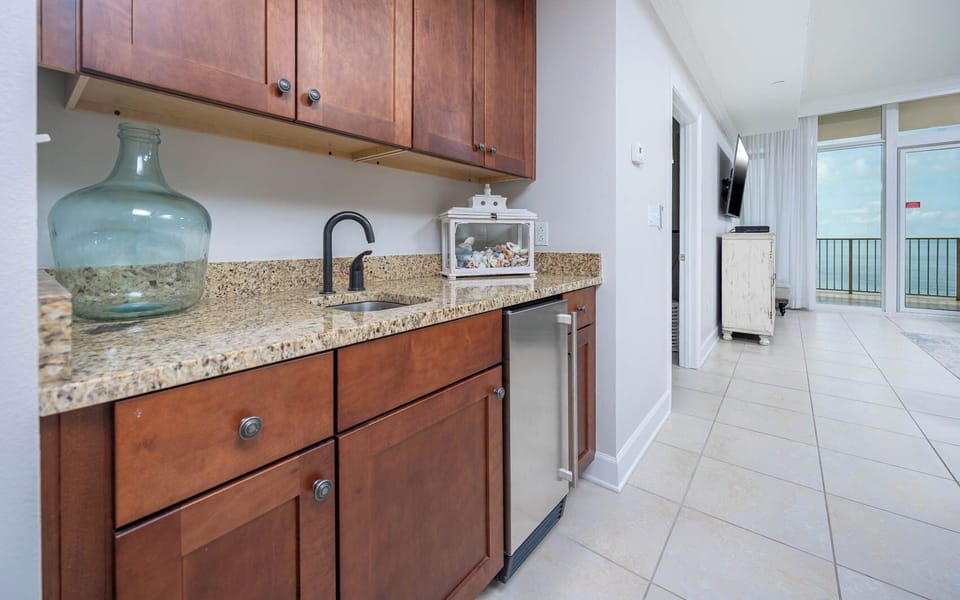 Prepare snacks and drinks at the stylish wet bar while enjoying beachfront views through the balcony windows
