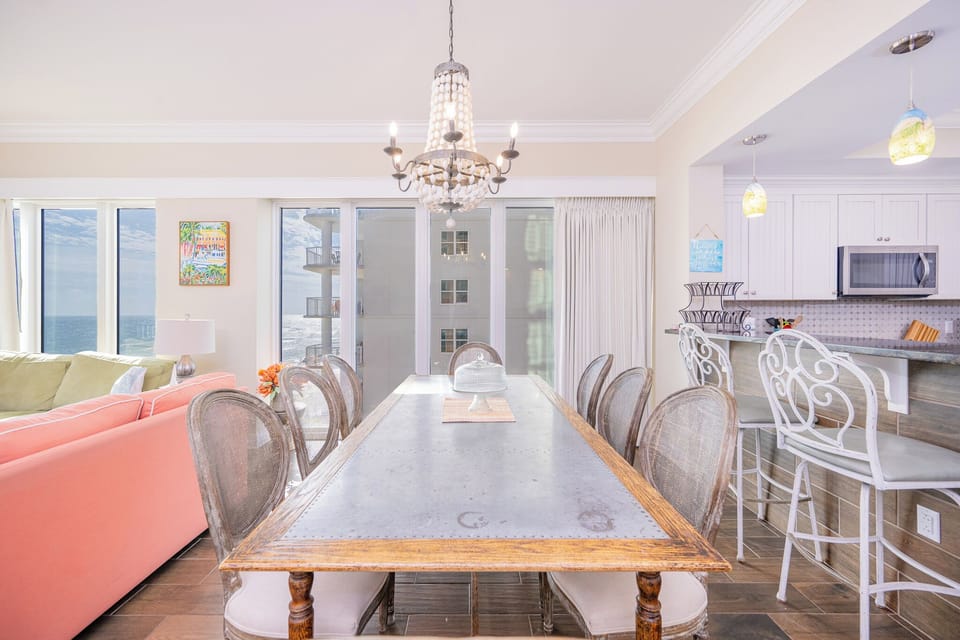 Dine at the stylish table with stunning beach views, complemented by colorful seating and coastal decor
