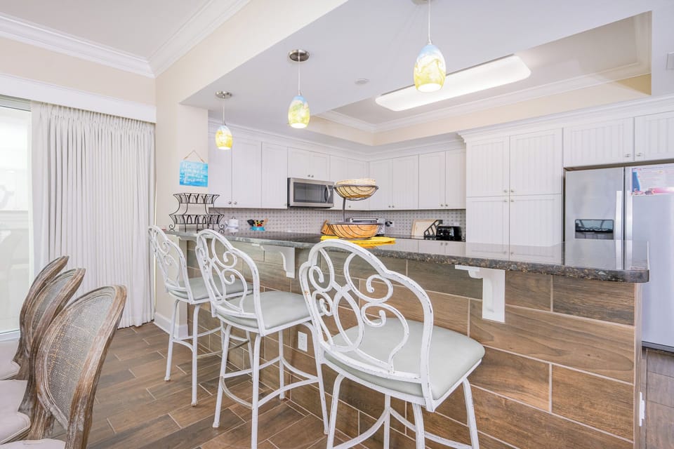 Gather around the stylish bar seating, enjoying the open layout and bright atmosphere of the inviting kitchen space