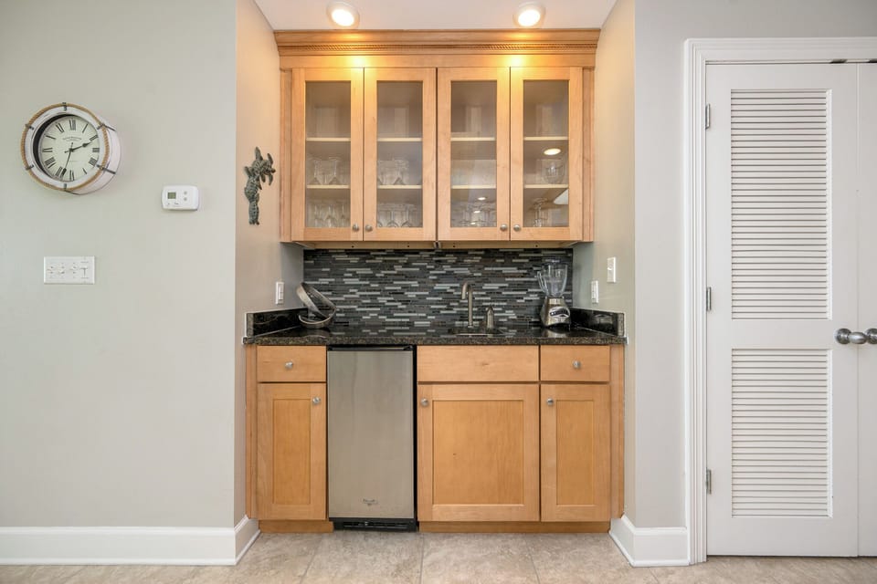 Enjoy preparing drinks at the stylish wet bar, featuring a stylish glassware display and stainless ice maker