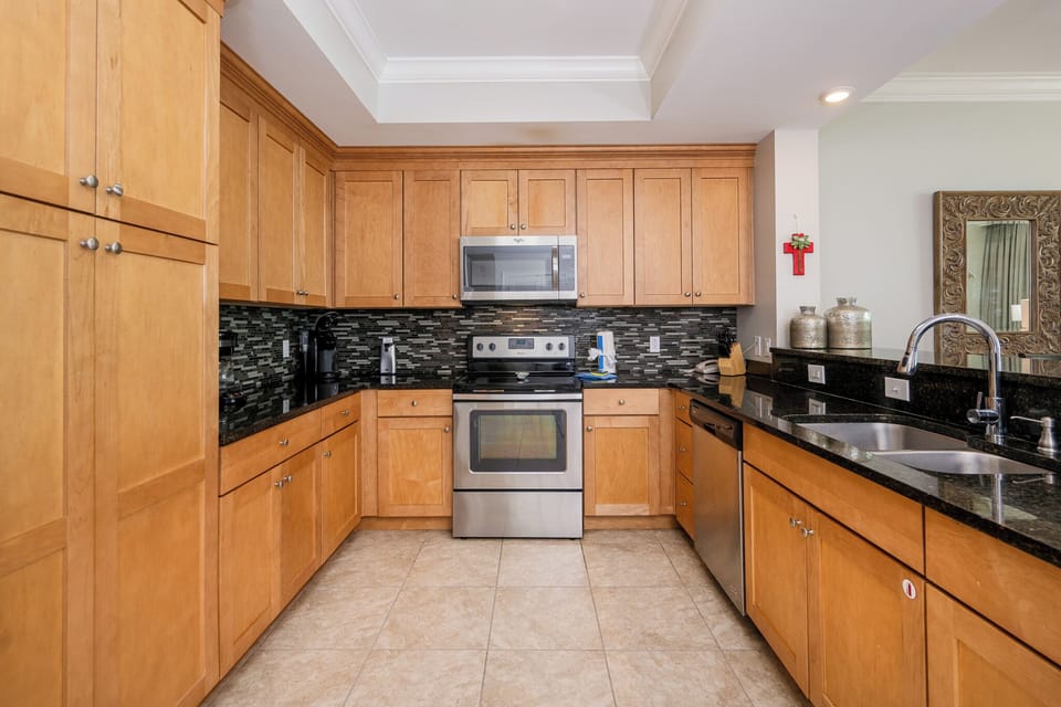Prepare meals in the warm-toned kitchen, featuring sleek appliances, coffee corner, and stylish backsplash