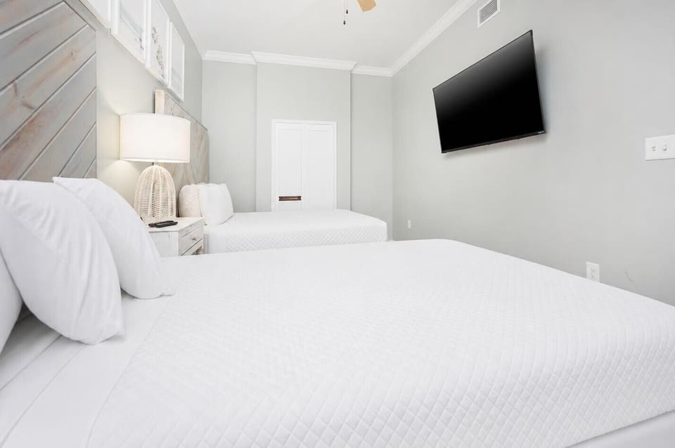 Rest and recharge in this guest bedroom, highlighted by plush queen bedding and a wall-mounted TV for entertainment