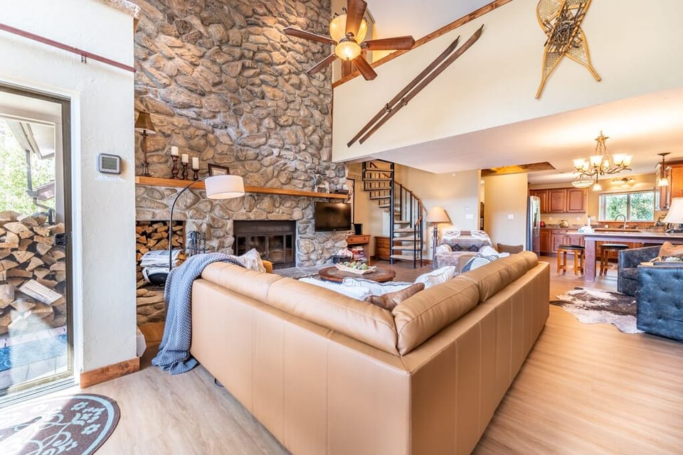 Unwind in your spacious living room featuring a stunning stone fireplace, leather sofa, and rustic charm with exposed beams.