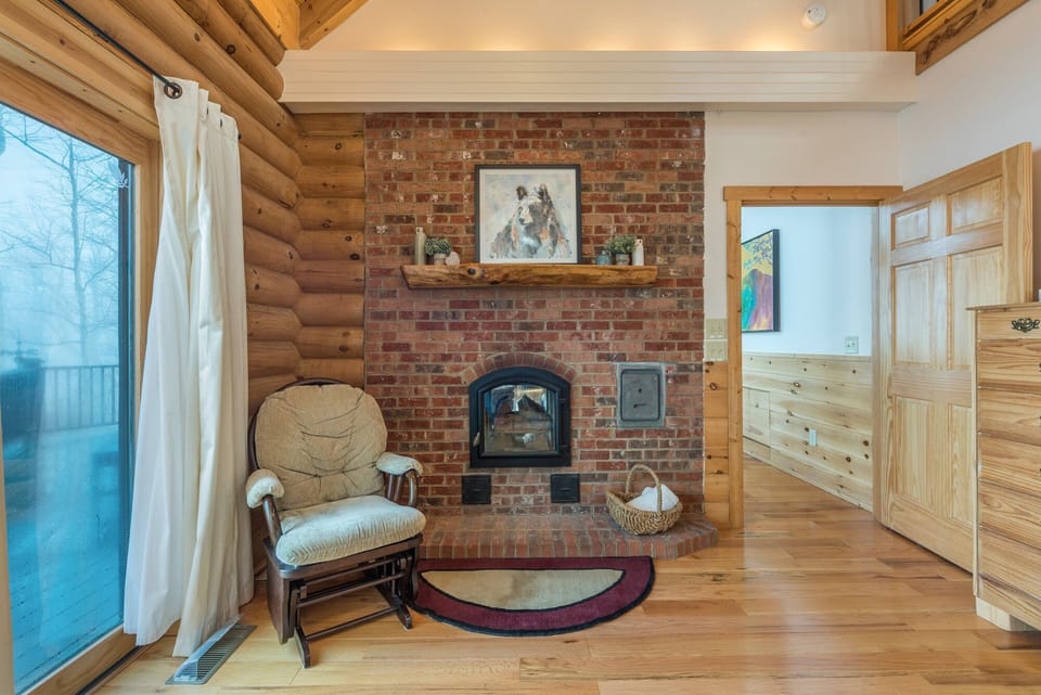 Main level primary bedroom with Queen bed, deck access, and en suite bath. Note: The fireplace is not functional.