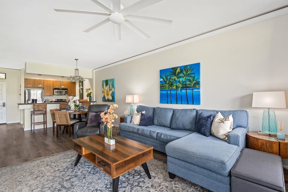 From another angle, sofa and kitchen connect, pendant lights and cabinetry framing the open plan.