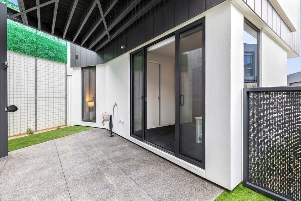 Sliding door access from the Single bed bedroom to a shaded courtyard. It has synthetic turf on a concrete base