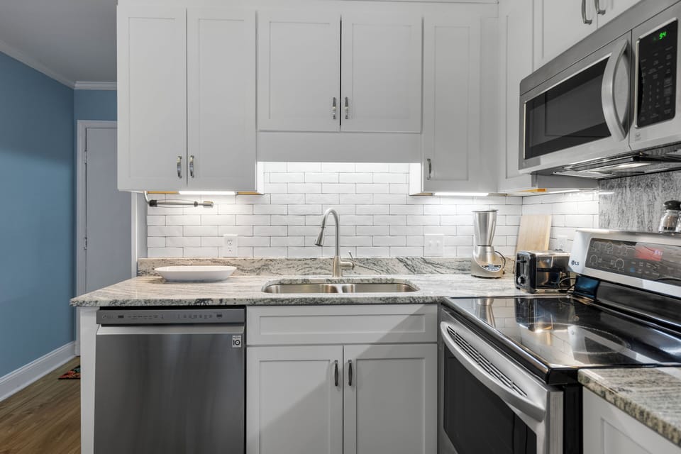 Your sleek kitchen features granite countertops, stainless steel appliances, and crisp white cabinetry with subway tile backsplash for effortless meal preparation.