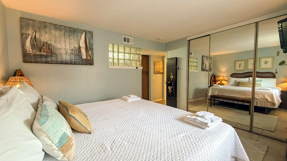 Your primary serene bedroom features a king bed, coastal artwork and mirrored closets that reflect natural light, creating an airy retreat for restful nights.