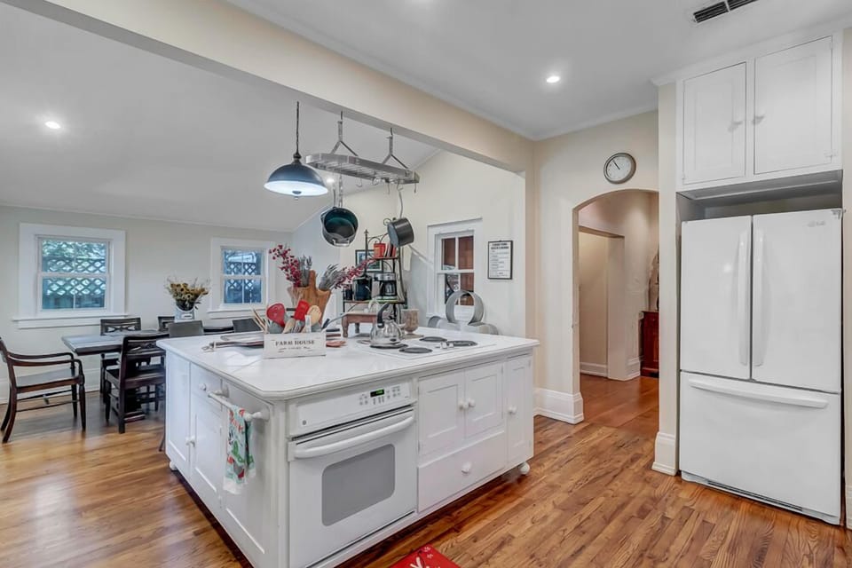 - Chef’s kitchen with central island, breakfast bar seating, and hanging pot rack
- Bright overhead lighting and prep ready counters for easy cooking or gathering
- French door fridge and vintage style oven enhance the kitchen’s unique charm