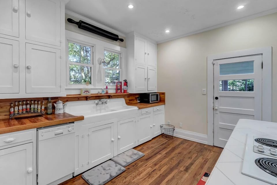- Butcher block counters and farmhouse sink overlook the garden through wide windows
- Crisp white cabinetry and charming wood accents give this kitchen timeless character
- Exterior door leads directly out to the patio or yard for al fresco ease