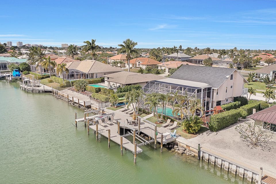 Aerial view of waterway, expansive dock   area w/ 8 lounge chairs, 4 seat table