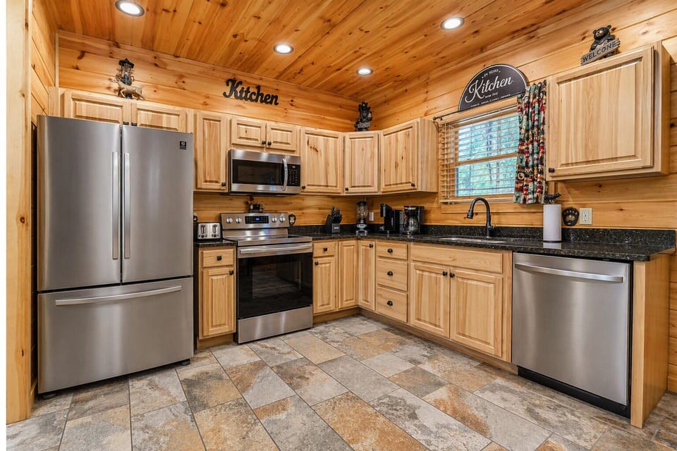 French‑door refrigerator and stainless‑steel appliances in a warm, bear‑themed kitchen
