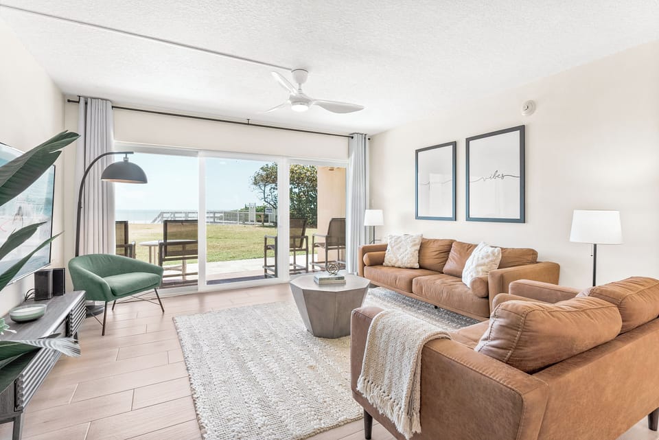 Bright and airy lounge featuring elegant decor, plush seating, and seamless access to the patio