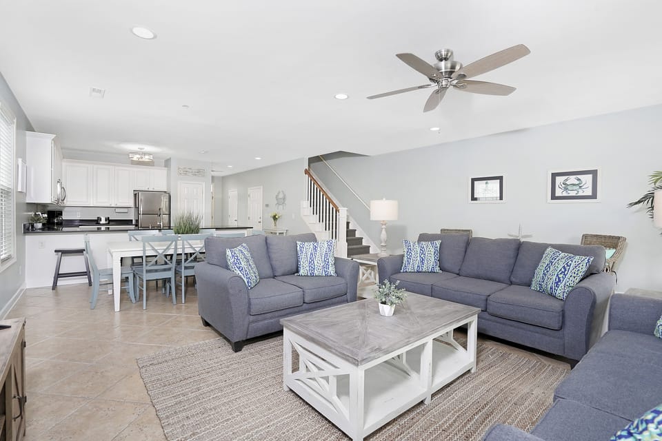 Relax in your spacious open-concept living area with plush sofas and ceiling fan keeping you comfortable.
