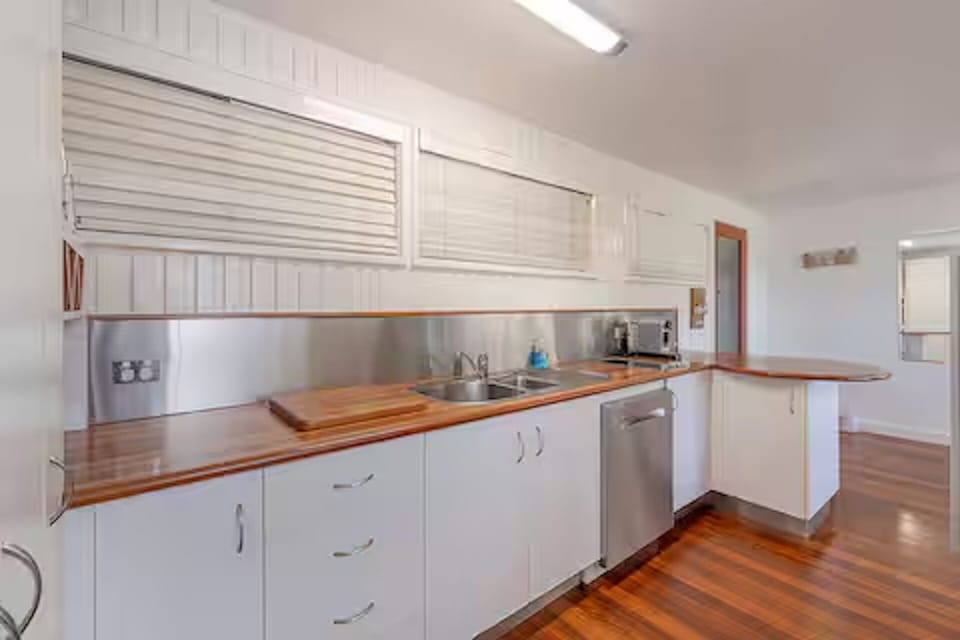 Full kitchen with oven, stove, fridge, microwave, pots, pans, and crockery.