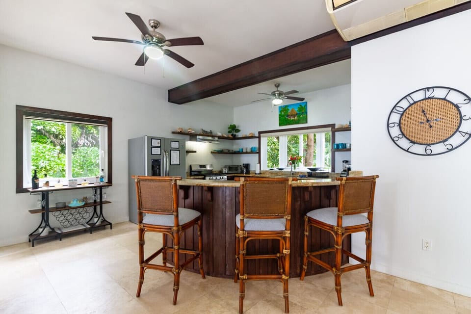The bar area serves as a versatile centerpiece, with three barstools on one side for casual seating and a spacious counter on the other, ideal for meal prep or serving drinks and snacks.