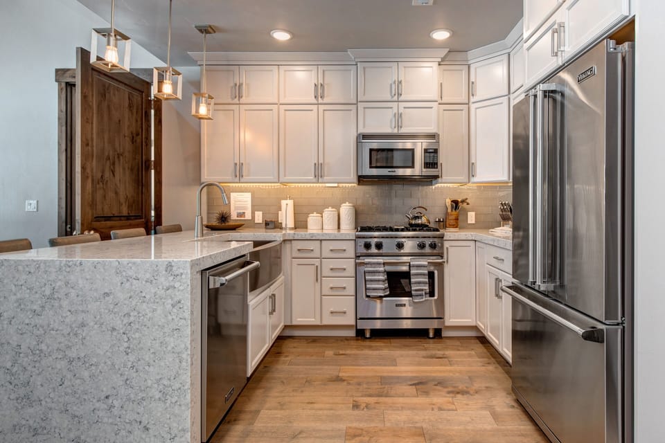 Fully Equipped Gourmet Kitchen with opulent stone countertops, stainless steel Viking appliances, and bar seating for four