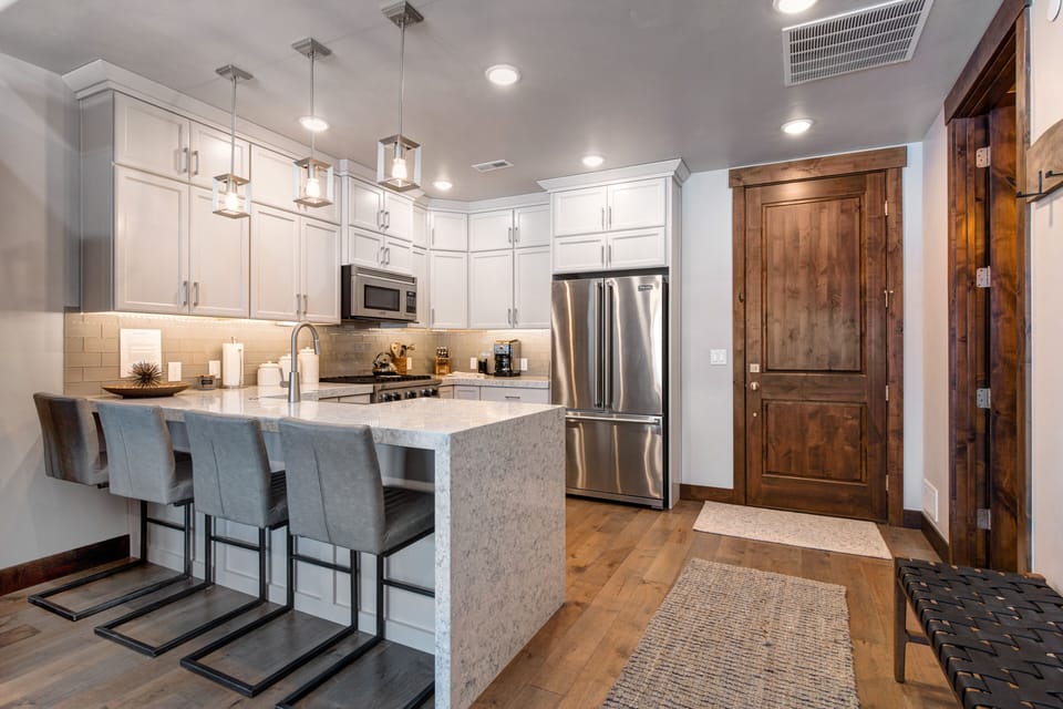 Fully Equipped Gourmet Kitchen with opulent stone countertops, stainless steel Viking appliances, and bar seating for four