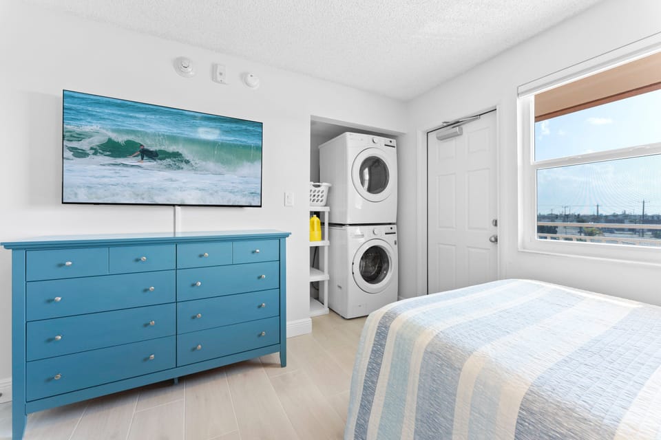 A stylish bedroom with a TV, dresser, and in-unit laundry for ultimate convenience.