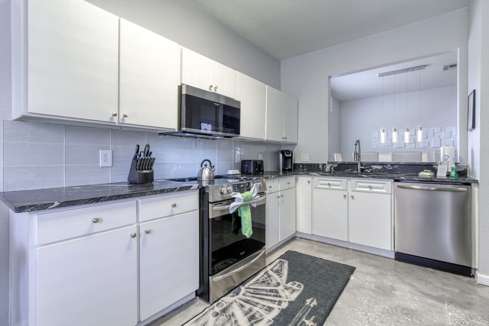 The fully equipped kitchen features stainless steel appliances and black leather granite countertops.