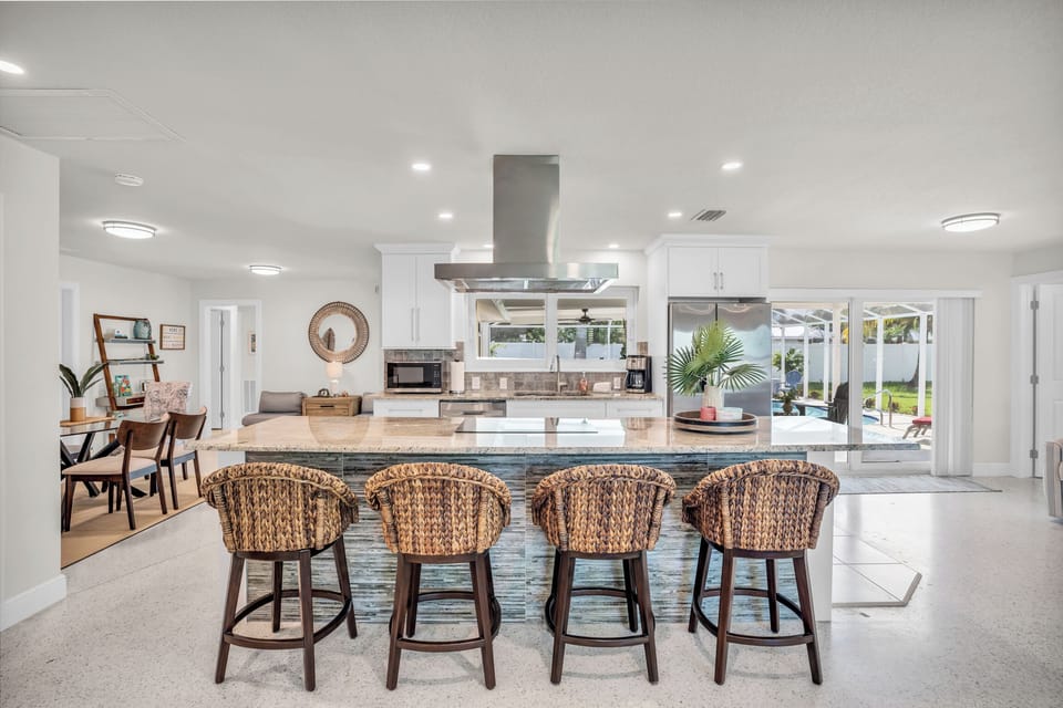 Modern kitchen with island seating and poolside view, perfect for entertaining.
