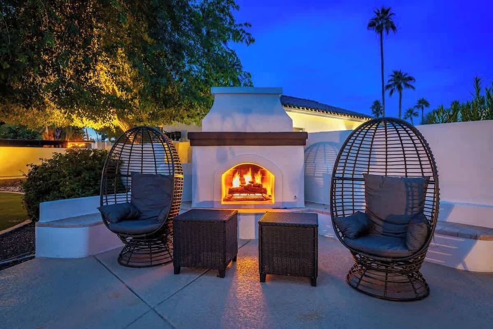 Relax in cozy pod chairs beside the glowing outdoor fireplace as palm trees sway above and the evening sky deepens. Perfect for unwinding under the stars after a day exploring.