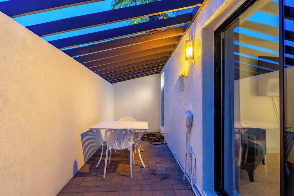 Your private patio offers an intimate outdoor retreat with a cozy dining set under a slatted pergola, perfect for evening meals beneath the stars or morning coffee in tropical warmth.