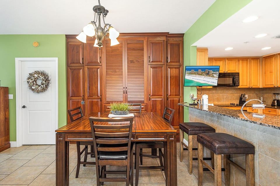 Gather around your spacious dining table where warm wood tones and coastal green walls create the perfect backdrop for memorable meals together.