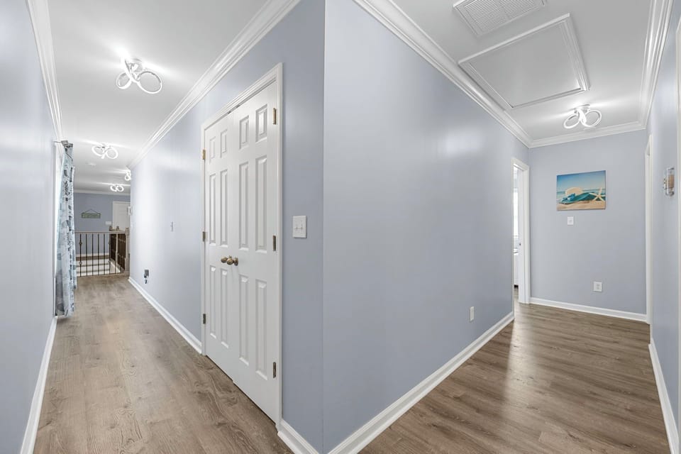 This hallway exudes a sense of calm with its soothing light blue walls, contrasting with crisp white doors and trims.
