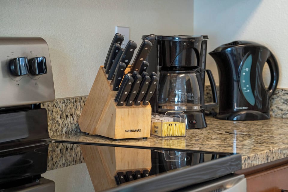 This kitchen corner boasts a sleek granite countertop with a stylish knife block and premium appliances, including a polished coffee maker and electric kettle, making meal preparation a delightful experience.