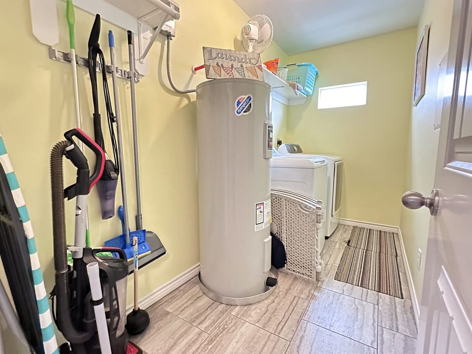 Separate laundry room includes washer, dryer, cleaning supplies and pool towels.