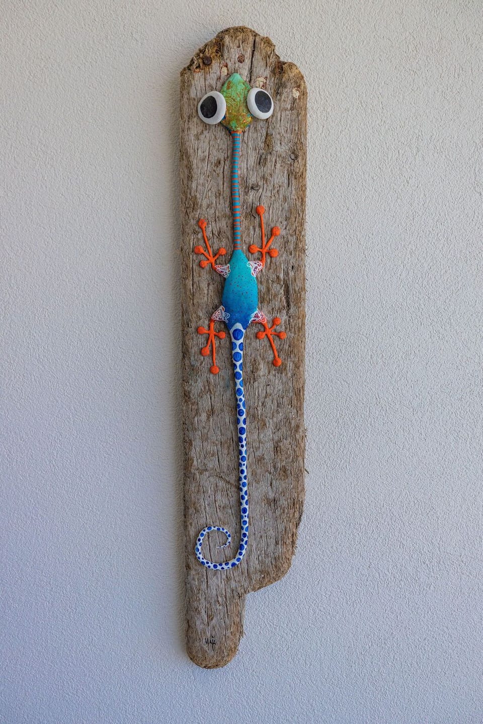 A whimsical gecko sculpture adorns the wall, crafted from driftwood and bright blue beading, adding playful tropical character to your retreat.