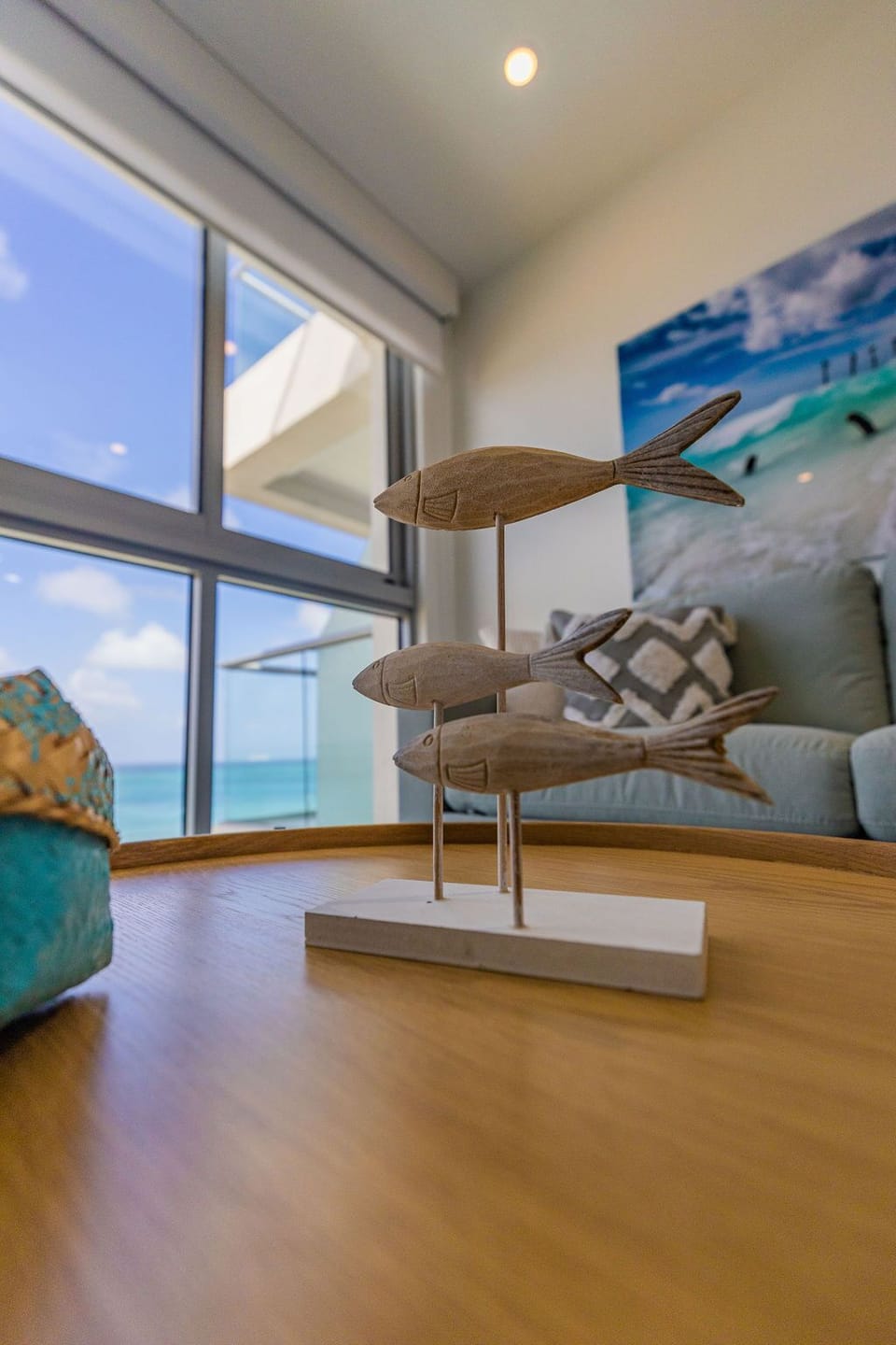 Relax on the sofa surrounded by beach-inspired décor and let the stunning turquoise sea views through expansive windows instantly transport you to coastal paradise.