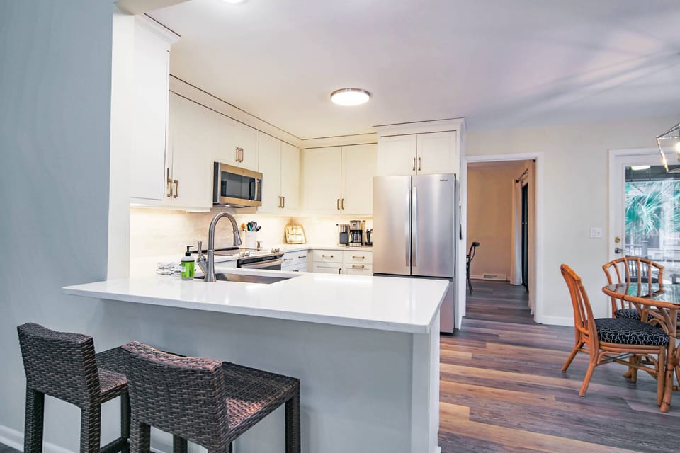 There is a dining table in the kitchen and the dining room is accessible through the doorway in this photo.