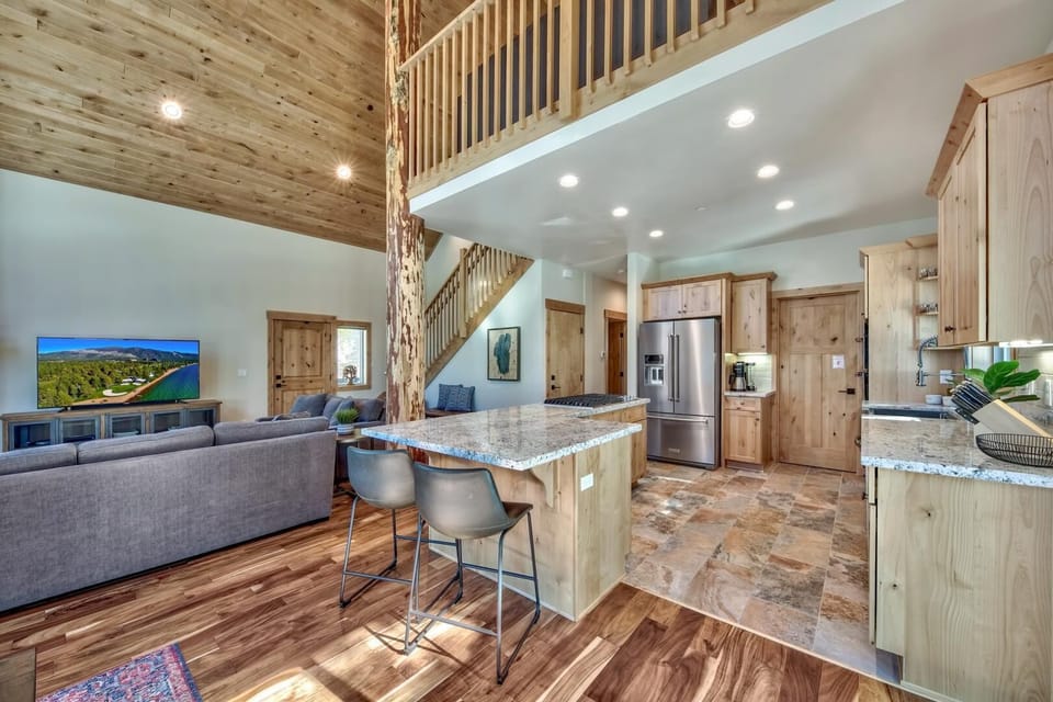 Gather around the granite island in this stunning open-concept space, where rustic wood meets modern comfort beneath soaring ceilings.