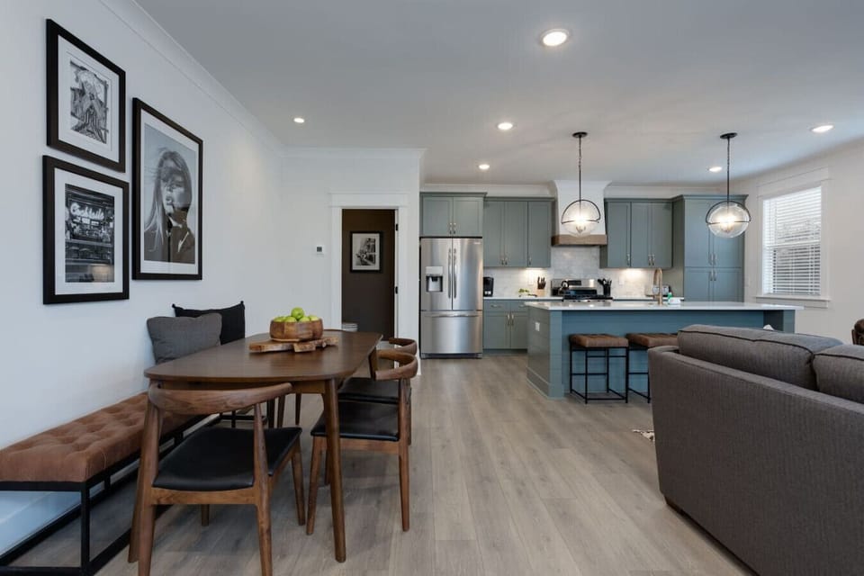 Kitchen and dining area with teal cabinets, marble countertops, and pendant lights