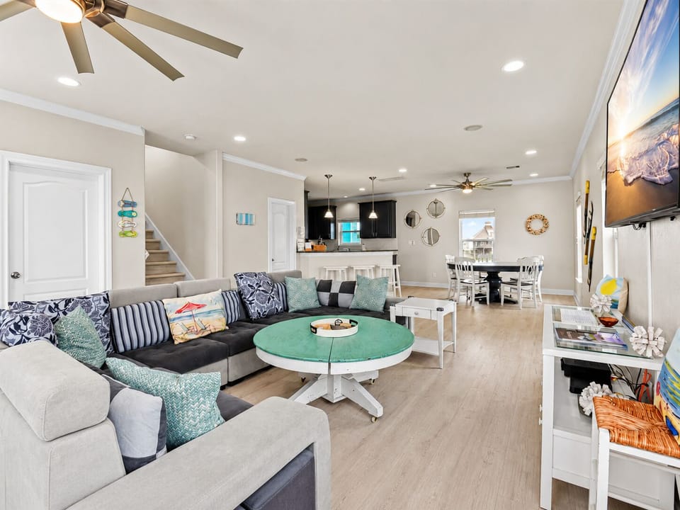 Open living and dining area with a large sectional sofa, coastal furnishings, Smart TV and easy access to the kitchen.