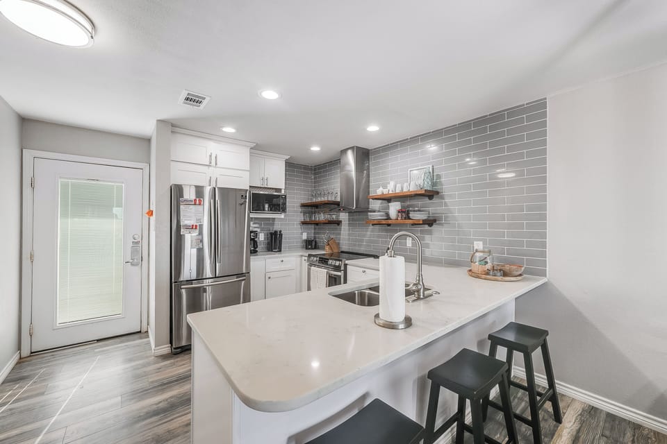 Your sleek modern kitchen features gleaming countertops, stainless appliances, and stylish subway tile backsplash perfect for creating memorable meals.