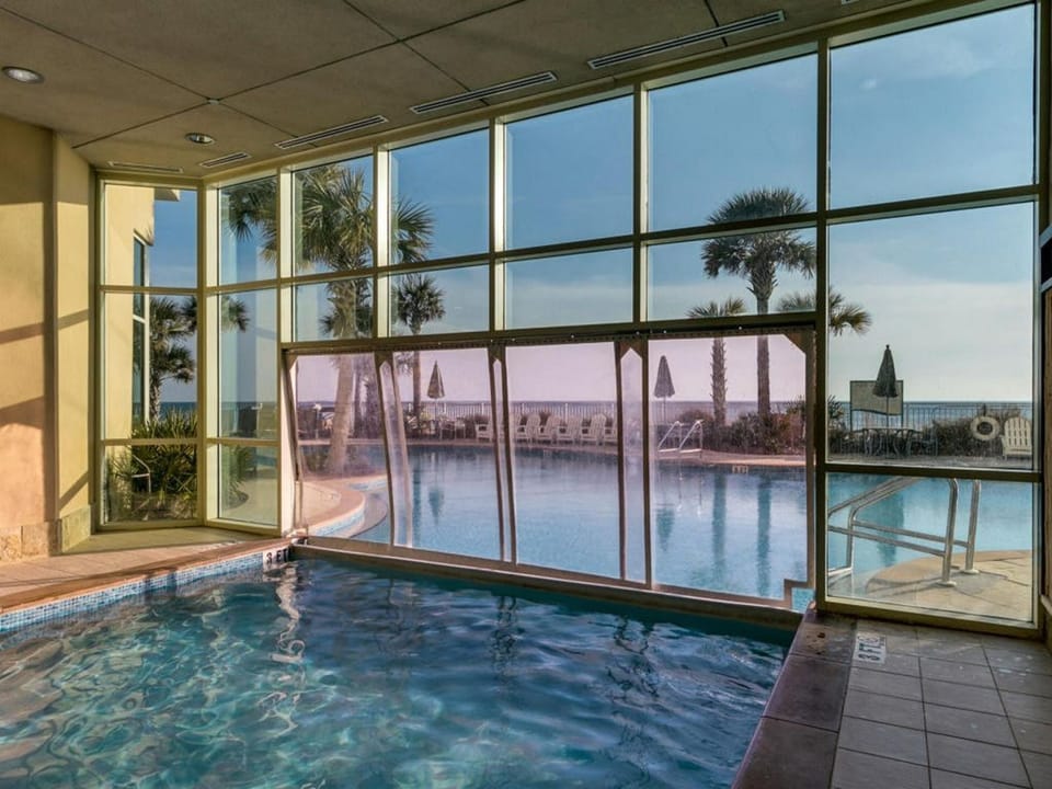 Unwind in your private indoor pool with panoramic views of the outdoor pool deck and palm-lined coastline beyond.