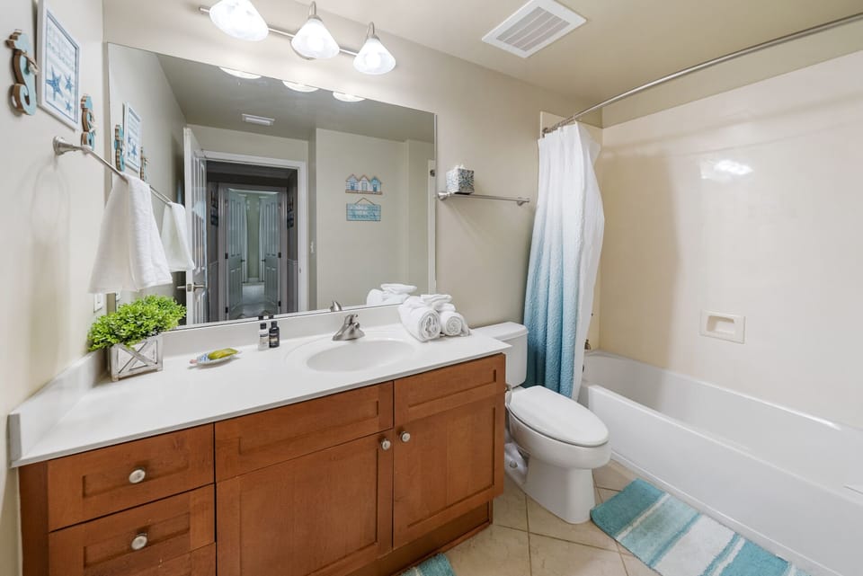 Refresh in your bright, modern bathroom with fresh towels, coastal décor, and a relaxing tub.