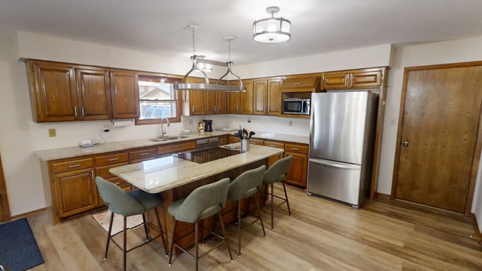 Gather around the spacious kitchen island where warm wood cabinetry, modern stainless appliances, and comfortable seating create your perfect space for cooking and connecting with family and friends.
