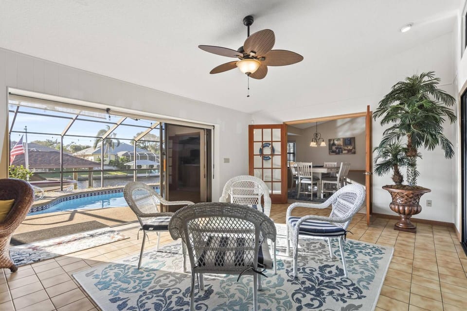 Ample seating area with views of the pool and canal, featuring patio doors that open directly to the pool deck and a Smart TV for entertainment.