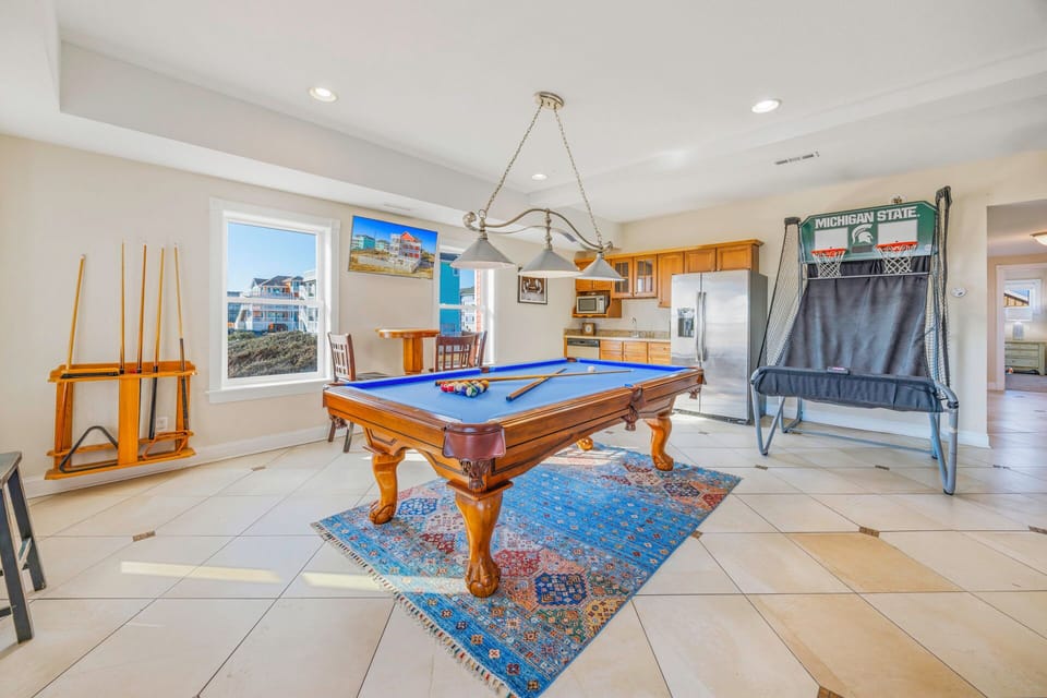 Challenge friends to pool games in your entertainment space with a professional table and arcade basketball setup.