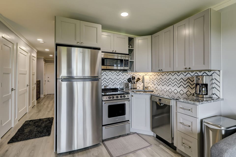 Sea Side Villa 122 Kitchen - All new stainless appliances, granite counters, tile backsplash and wood cabinets make up the fully equipped kitchen.  Wood grain tile flooring is throughout the condo.