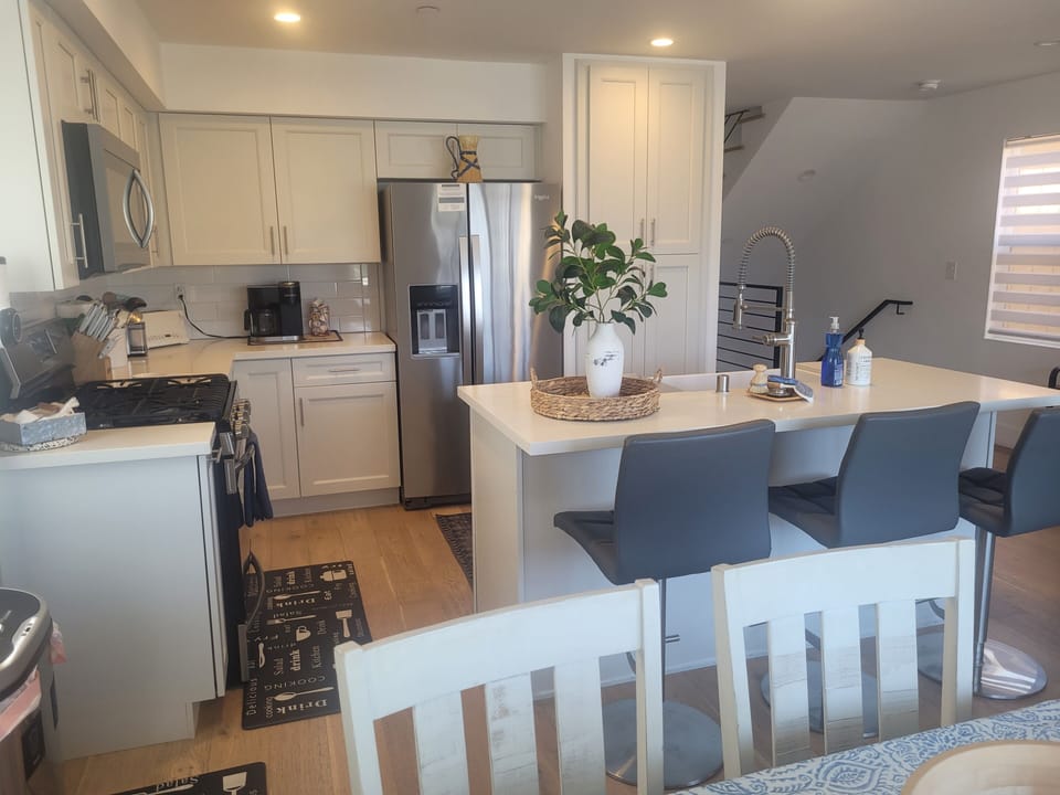 microwave, indoor dining,  coffee bar chefs kitchen, oven, stainless refrigerator with chilled filtered water and ice, stovetop, dining table and kitchen bar